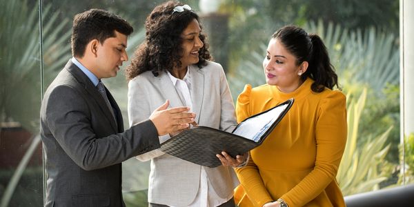 Three professionals reviewing documents together in a bright office setting.