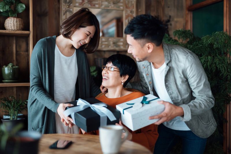 A senior Asian mother receiving presents from her daughter and son at home. Family love. The joy of giving and receiving