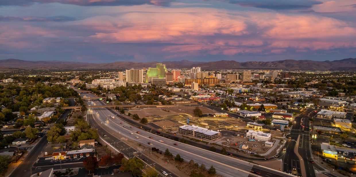 A cityscape at sunset with highways and buildings under a colorful sky.