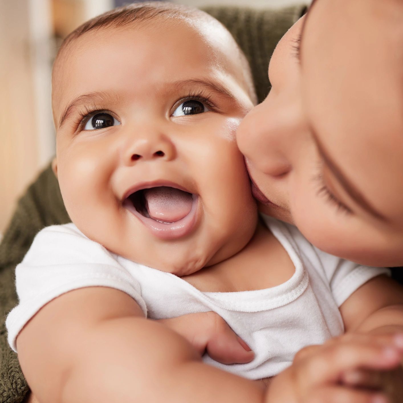 Smiling baby being kissed by mother – postpartum support in the Greater Boston Area.