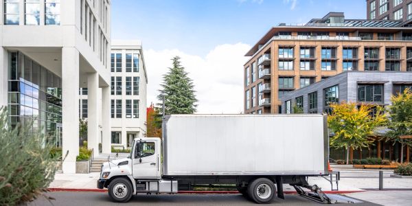 A white delivery truck parked in an urban area with modern buildings.