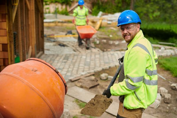 Construction workers paving an outdoor area with bricks and cement.