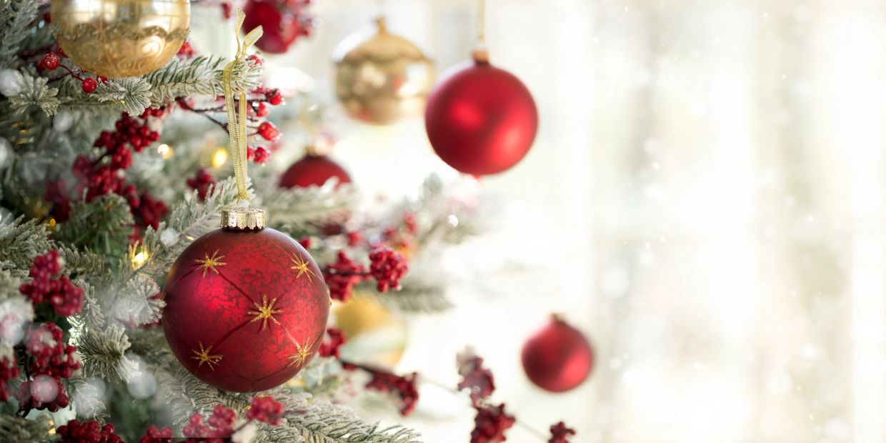 Red and gold Christmas ornaments on snowy pine branches.