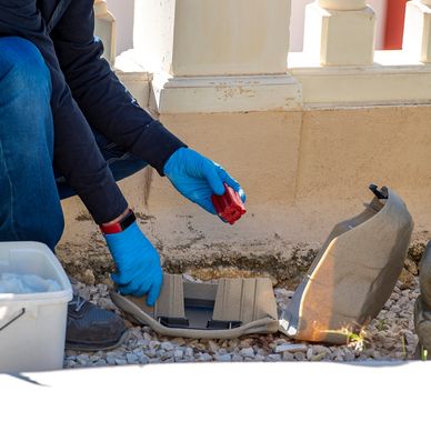Person in blue gloves working on hidden compartment outdoors.