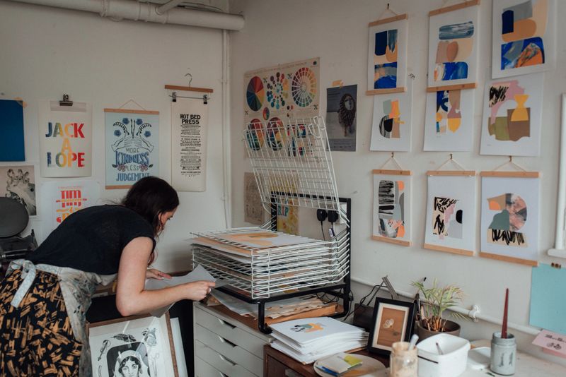 Printmaker putting wet prints onto a drying rack