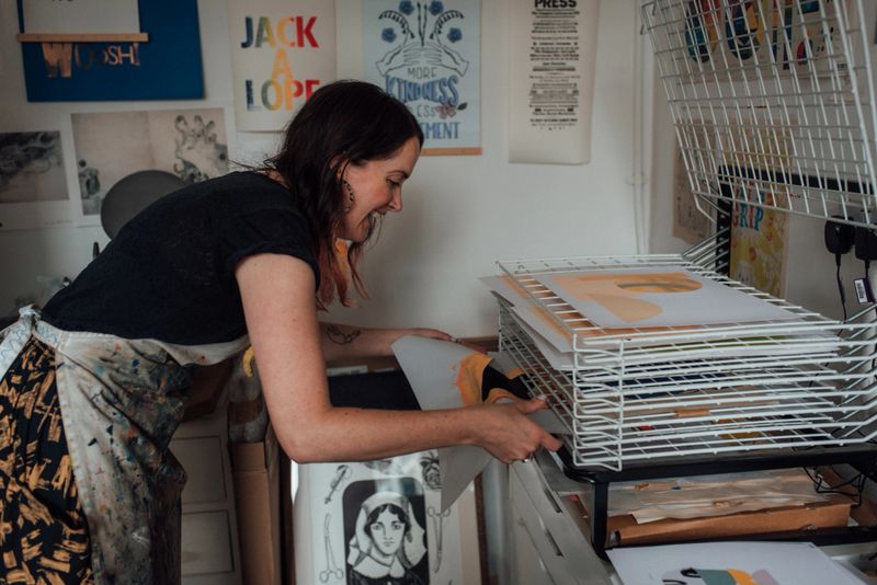 Printmaker putting wet prints onto a drying rack
