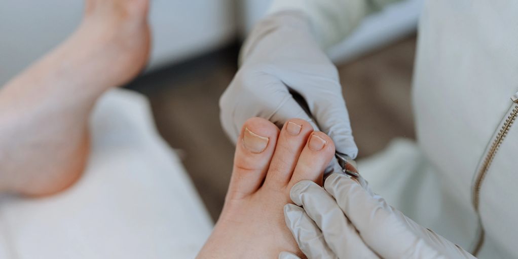 Soins des ongles de pieds par un professionnel en gants.