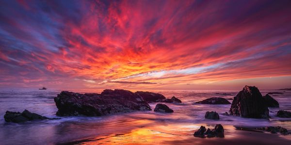 Sunset over coastal cliffs and ocean rock formations.