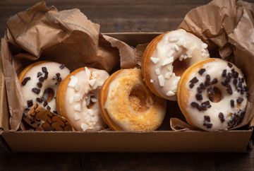 Box of assorted donuts with icing and toppings.