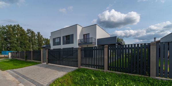 Modern house with a dark fence and green lawn.
