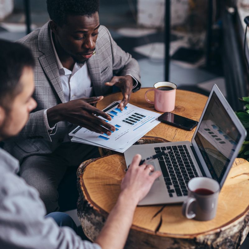 Business men review data at an informal cafe meeting.