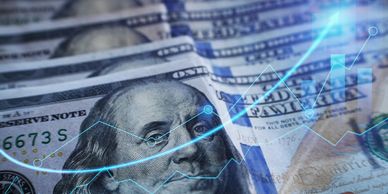 Close-up of US $100 bills with a rising financial graph overlay.