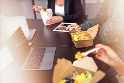 People eating takeout food while working on laptops and tablets.