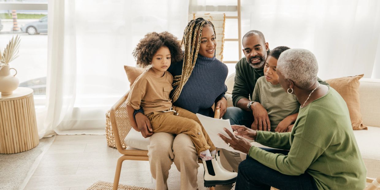 Family gathered and looking at a paper together indoors.