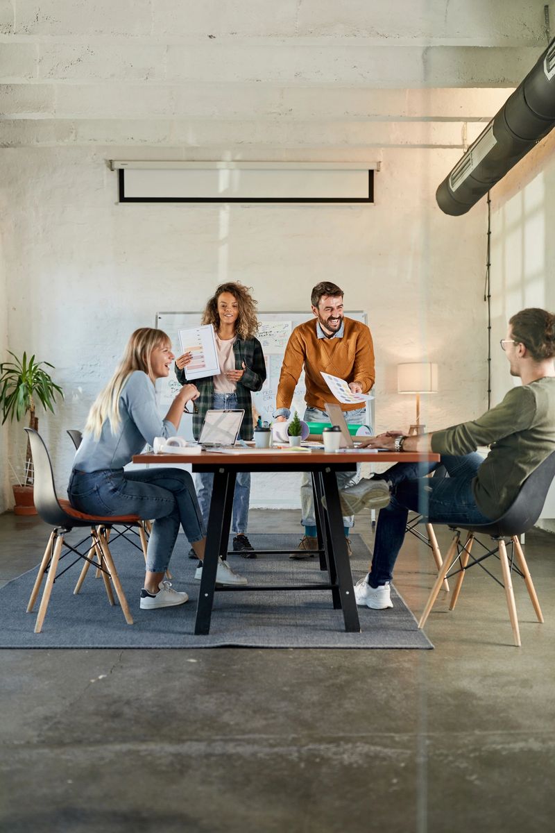 Group of happy freelancers talking about paperwork during a meeting at casual office. Copy space.