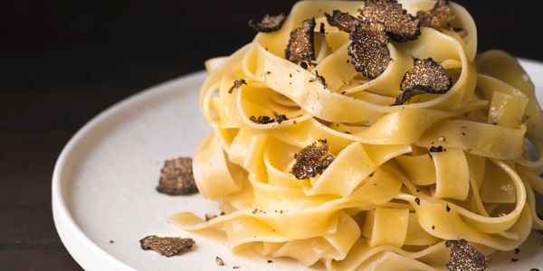 Tagliatelle pasta garnished with black truffle slices on a white plate. Gnocchi dishes, Italian Restaurant, Philadelphia dining