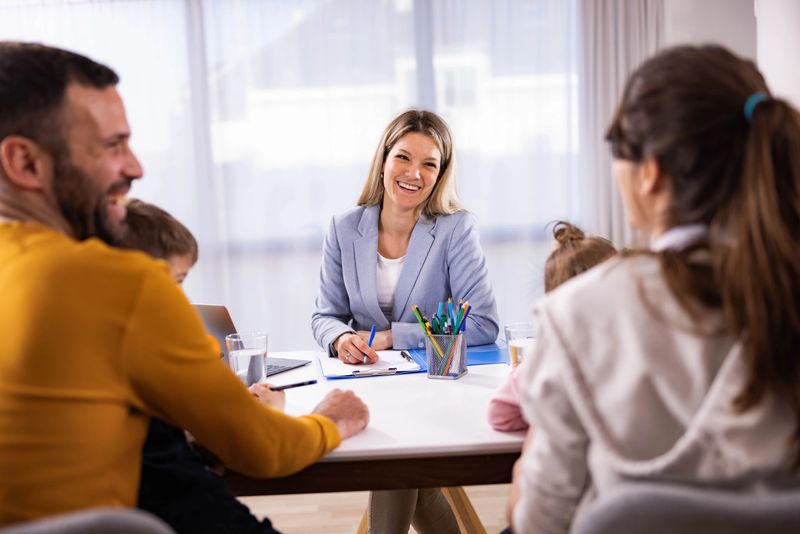 Female school principal talking to a family about children's education in the office.