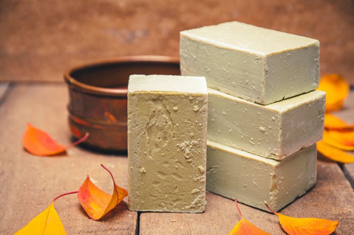 Natural soap bars stacked with autumn leaves on a wooden surface.