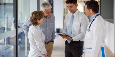 Doctors and professionals discussing patient information in a hospital corridor.