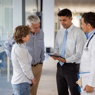 A doctor and professionals discussing information on a tablet with two people in a modern office.