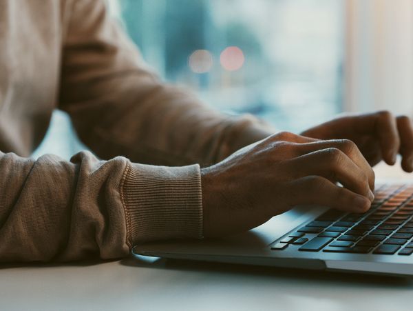 Hands typing on a laptop keyboard.
