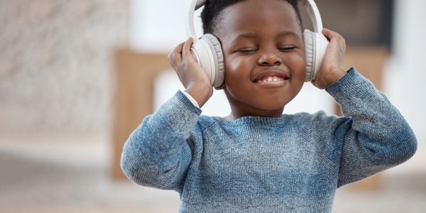 Young boy enjoying music with headphones on, eyes closed and smiling.