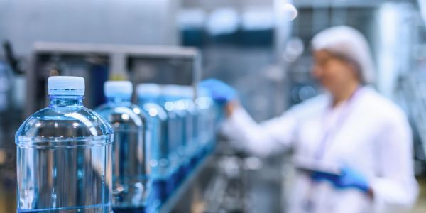 Line of plastic bottles on conveyor belt in factory.