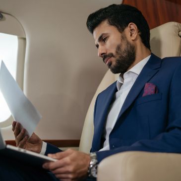 Businessman in a blue suit reviewing documents on a private jet.