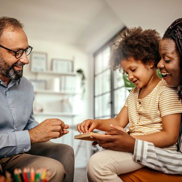 A joyful family playing a board game together indoors.