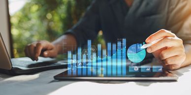 Person analyzing data charts on a tablet with a stylus and laptop.