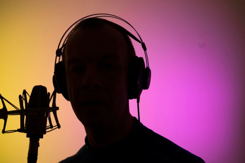 Voiceover artist voice actor in vocal recording studio with larg diaphragm microphone and antipop shield.