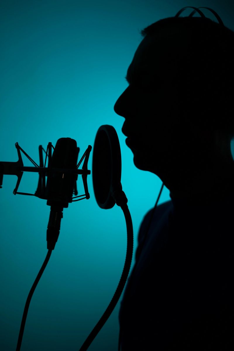 Voiceover artist voice actor in vocal recording studio with larg diaphragm microphone and antipop shield.