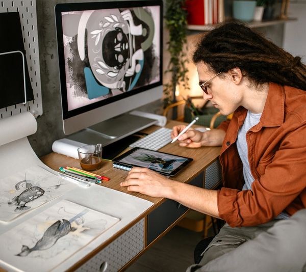 Artist working digitally and traditionally at a desk.