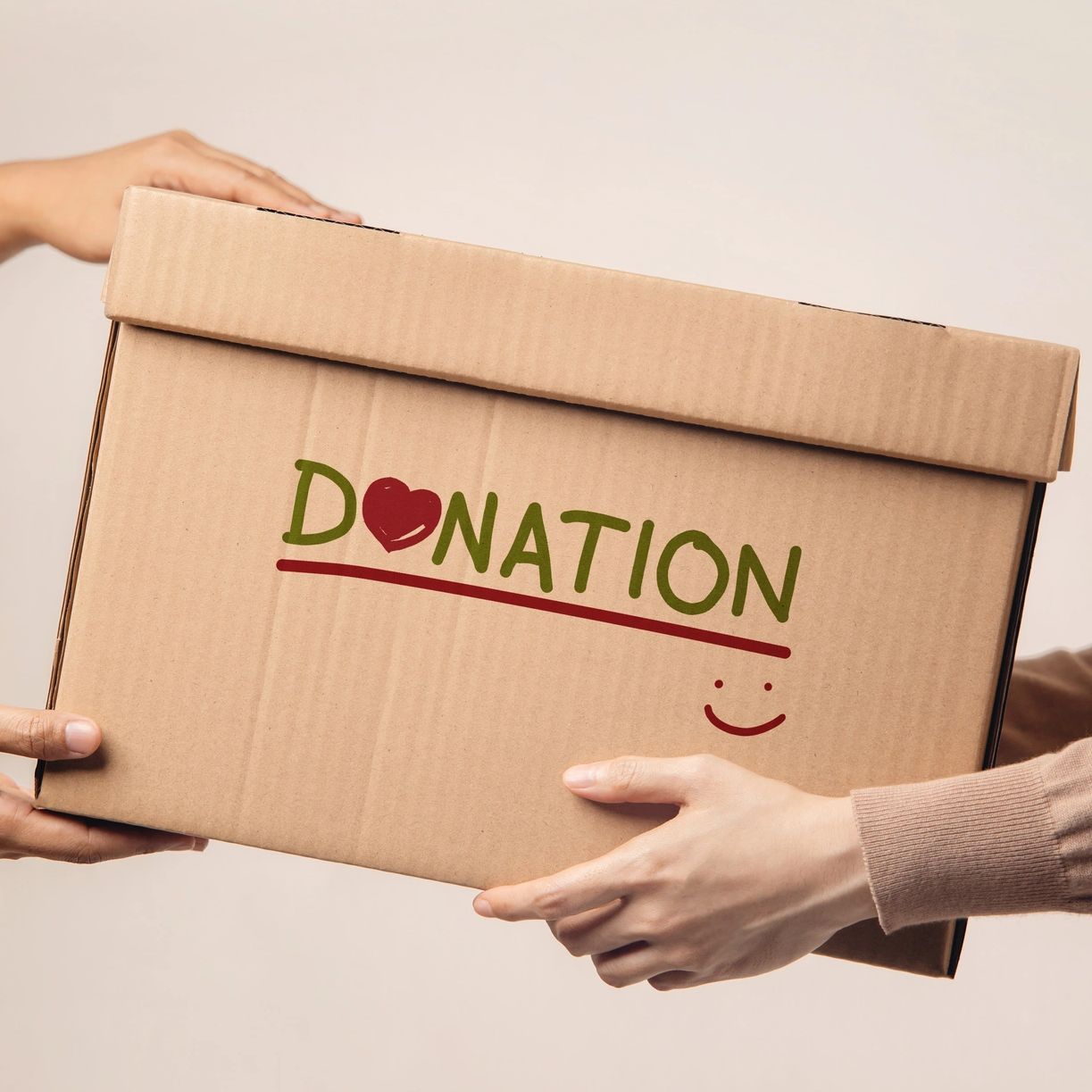 Two people exchanging a cardboard box labeled "DONATION" with a heart and smiley.