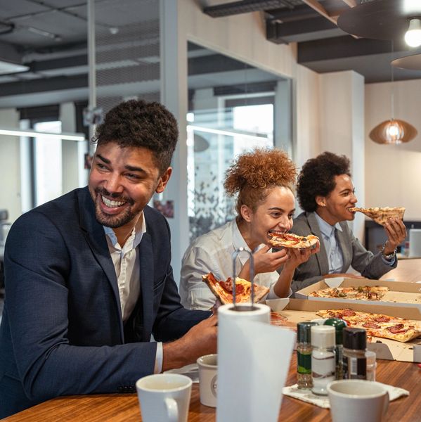 Friendly pizza server offers pizza to happy customers.