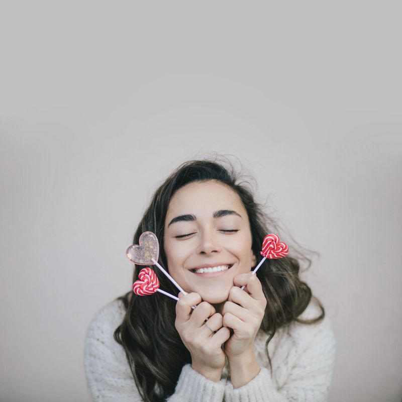 Young beautiful woman posing with Valentine's day heart shaped candies and lollipops. Place for text.