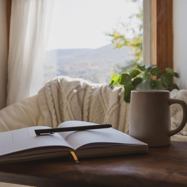 Pencere kenarında açık defter, kalem ve kupa.