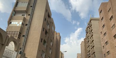 Tall beige and brown buildings under a partly cloudy sky.