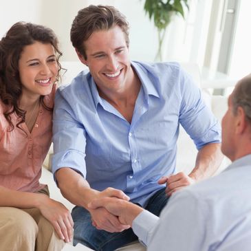 Couple shaking hands with a professional in a bright office setting.