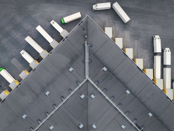Aerial view of trucks parked at loading docks beside a large warehouse.