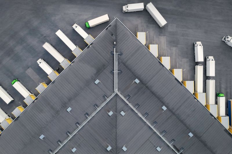 Aerial view of a large distribution warehouse with loading docks and many trucks.