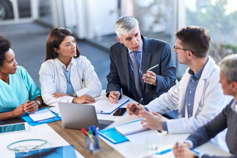 Group of medical experts having a business meeting with businessman in a hospital.