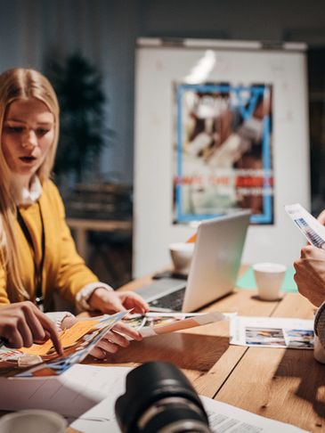 Team collaborating over printed photos and documents in an office setting.