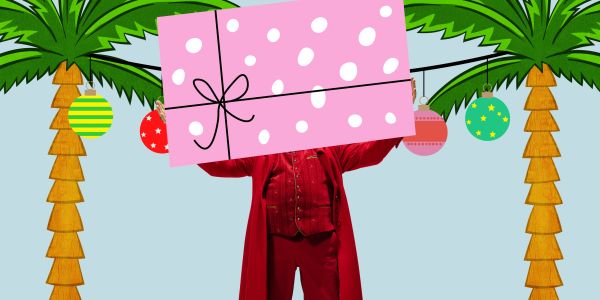 Person in red holding a large pink polka dot gift with decorated palm trees.