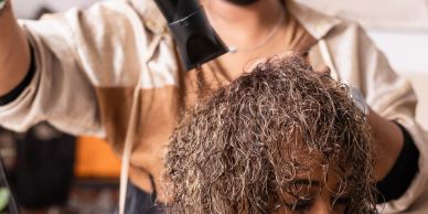 A person blow-drying another person's curly hair.
