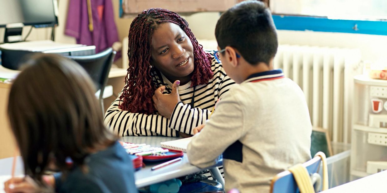 Teacher engaging with a student one-on-one in a classroom.