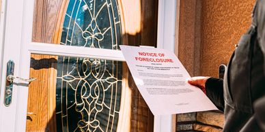 Person holding a foreclosure notice at a decorative glass door.