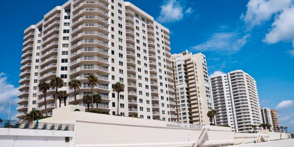 Tall white beachfront condos under a bright blue sky.