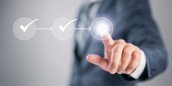 Businessman in suit tapping glowing checkmark icon in a progress sequence.