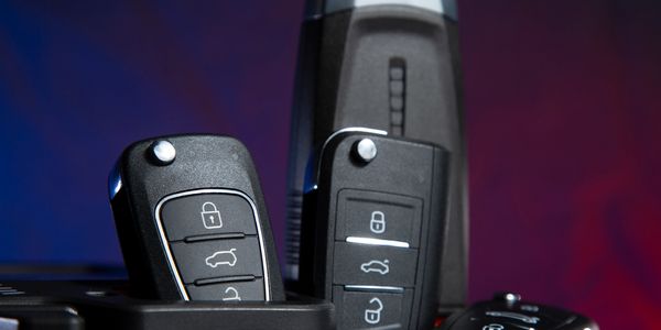 Close-up of multiple black car key fobs against a colorful background.